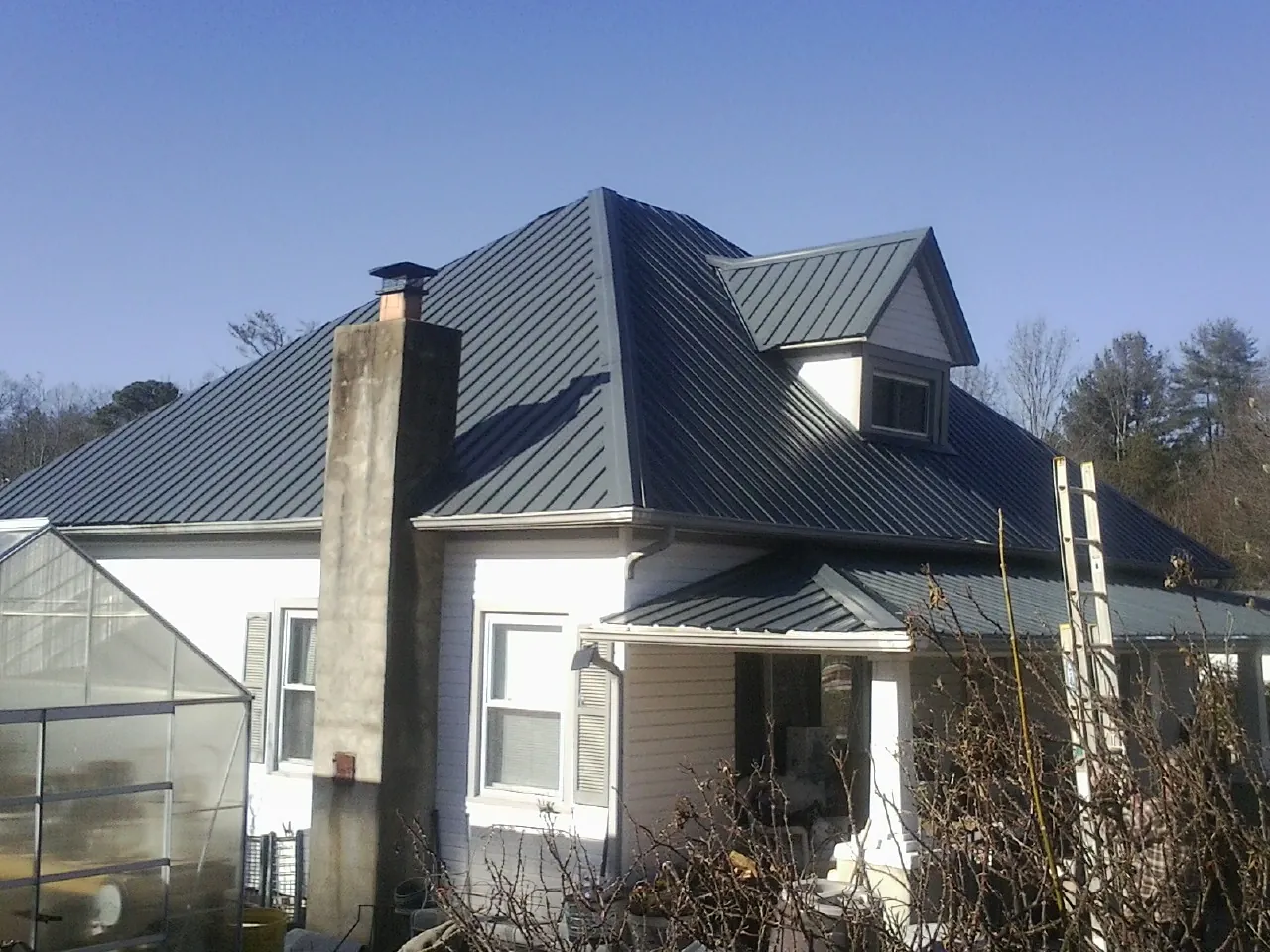 Dark blue standing seam metal roof on a white farmhouse with dormer — Slate & Tile Roof Repair by Roofing Brothers in Albion